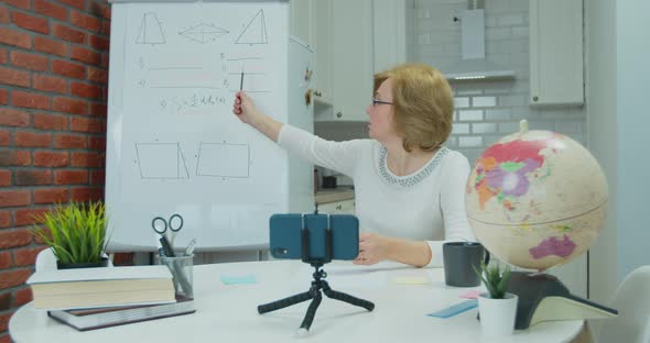 Adult Woman Teacher Recording Online Lesson on Smartphone Sitting at Home Office Desk