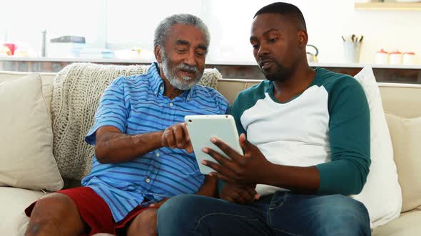 Father and son using digital tablet in living room