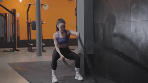 Wide Shot of Strong Young Caucasian Woman Doing Crossfit Exercise Using Ropes. Brunette Pretty