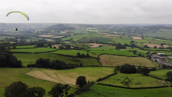 Aerial shot of a Paraglider flying over the Devon Countryside in England