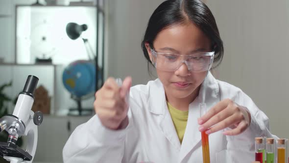 Asian Scientist Girl Mixes Chemicals In Test Tube And Note On Her Book. Child Learn With Interest