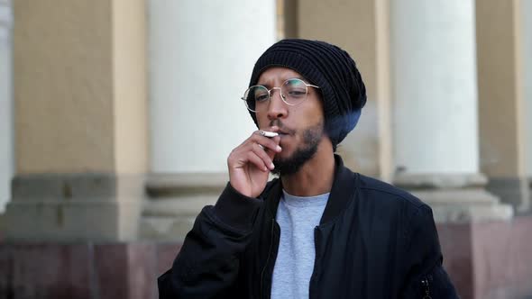 Stylish Pensive Man Takes a Puff of a Cigarette in Slow Motion Smokes on the Street