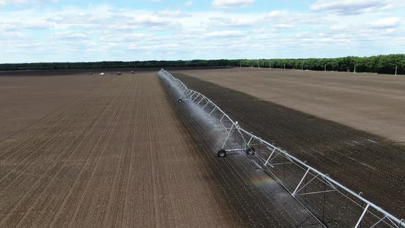 Huge Dry Field in the Summer Is Being Watered By a Modern Sprinkling Machine, 