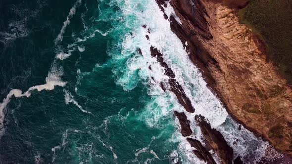White Surf at Base of Tall Cliff in Big Sur Cali, Wide Overhead Drone Shot