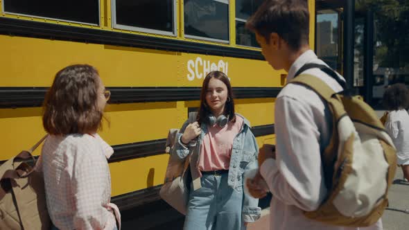 Students Standing Together Talking at School Bus