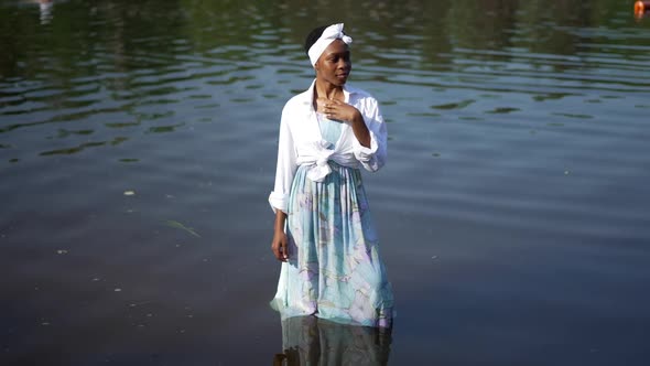 Gorgeous Young African American Woman in Dress Standing in River Water Looking Away Smiling