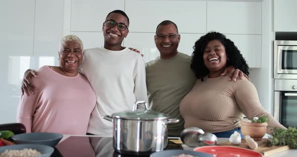 Happy latin family looking in camera and smiling - Parents and adult children having fun cooking