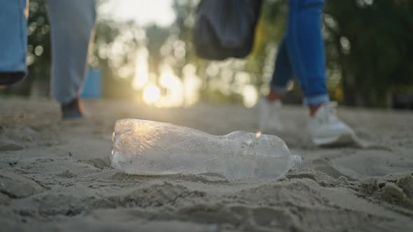 Volunteers Pick Up Thrown Bottle From Beach Sand at Sunset