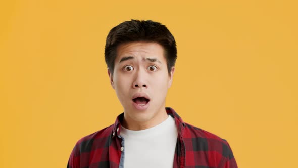 Shocked Asian Guy Looking At Camera In Surprise Yellow Background