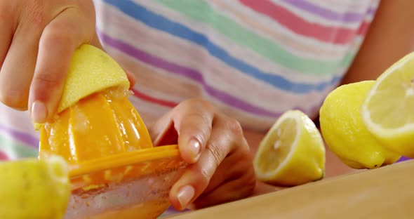 Woman preparing lime juice from juicer against violet background