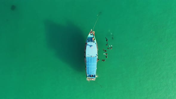 Aerial view of diving boat with a group of divers embarking in pristine beauty turquoise ocean water