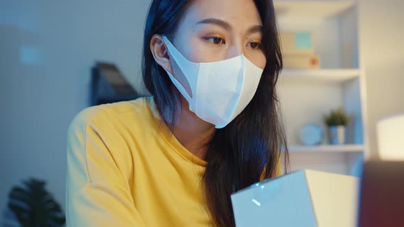 Young Asia businesswoman wear face mask check purchase order and reply client inbox chat on laptop.