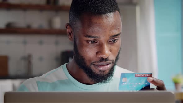 Closeup of AfricanAmerican Ethnicity Man Making Online Payment on Laptop with Credit Card