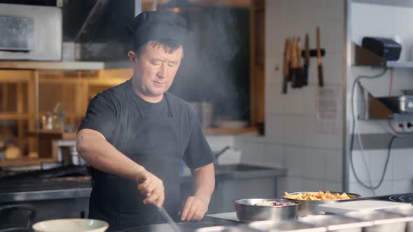 Confident Korean Male Chef in Uniform Preparing Tasty Hot Food on Stove