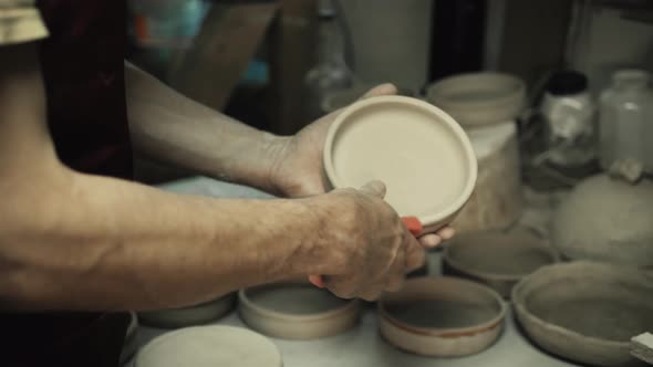Man Hands Makes Clay Plates in Pottery Workshop Top Close Up View Focus on Stained Hand