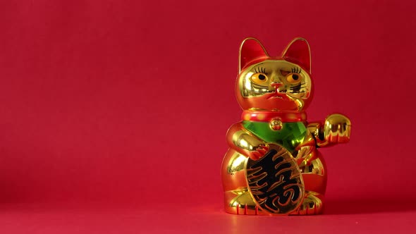 Sitting Maneki-neko cat waving with paw