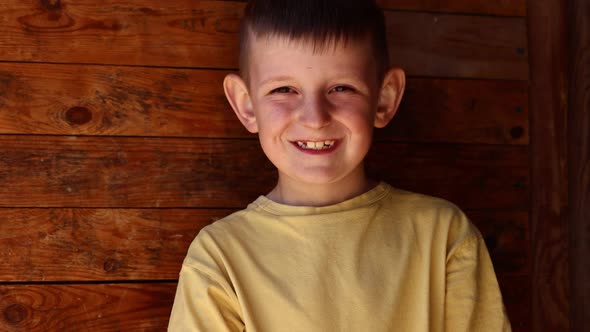 Cute little boy in a yellow t-shirt posing in front of a rustic wall. Portrait of a smiling male 