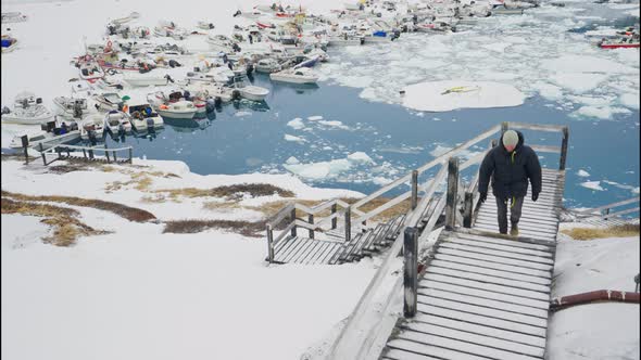 Man In Winter Coat Walking Along Walkway In Town Of Ilulissat