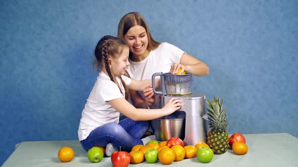 Happy mother and daughter squeezing fruits for juice. 