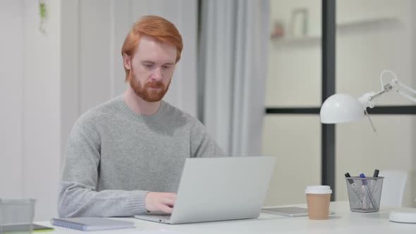 Beard Redhead Man with Laptop Looking at Camera at Work