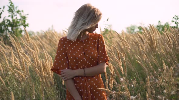 Portrait of a Young Attractive Blonde Woman in a Field with Spikelets at Sunset