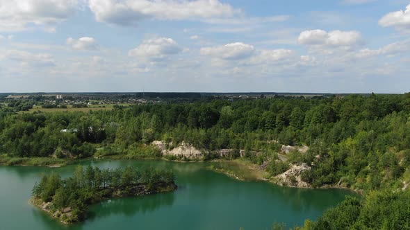 Aerial View of a lake with Beautiful Water in a Quarry Surrounded by Forest, Small Town and Mining O