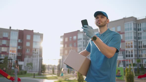 Male Courier Man is Looking for Mobile Phone to Deliver Address of Food From a Shop