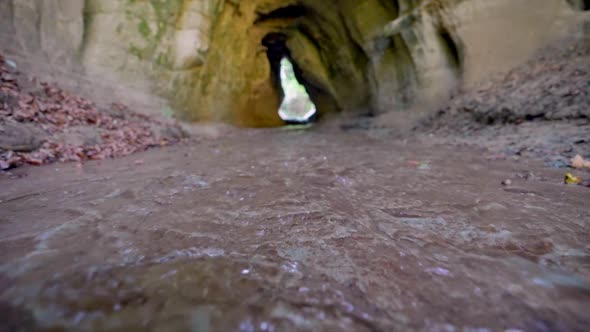 Low angle shot of natural stream flowing through cave during sunny day in autumn