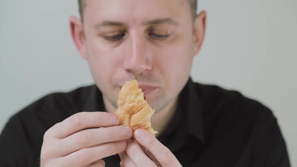 Man Eating Croissant with Egg and Sausage. Emotionally Chewing on the Bloodsucker. A Hungry Man
