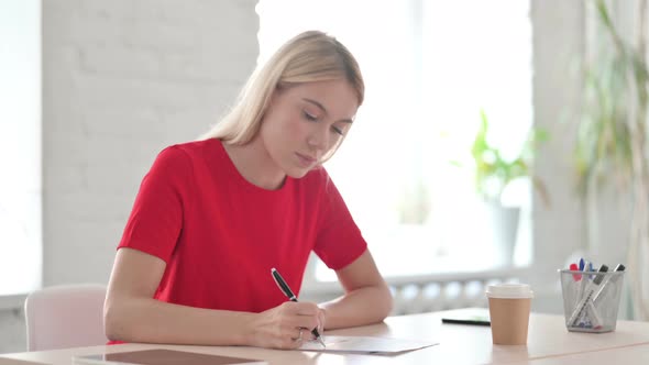 Young Blonde Woman Reading Documents, Doing Paperwork in Office