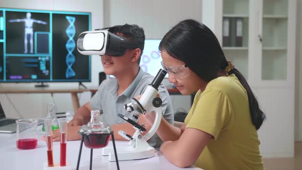 Asian Boy And Girl Learning Science Experiment In Laboratory. Study With VR Headset And A Microscope alt