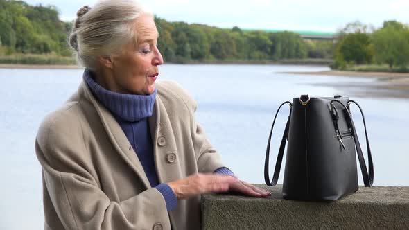 An Elderly Woman Dances with a Smile - a Lake in the Blurry Background