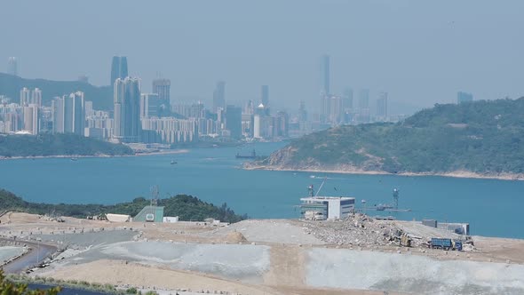 A Wide Landfill Area Next To The Coastline Of South China Overlooking The Skyline. -wide shot