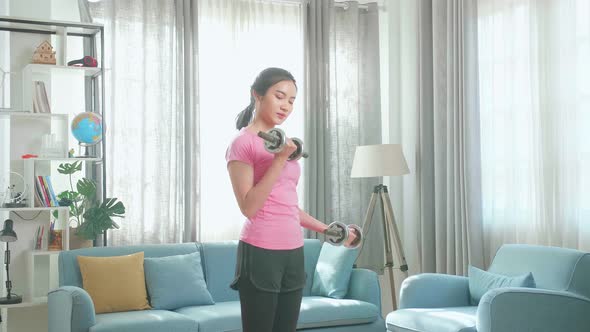 Young Asian Woman With Dumbbells Exercising At Home