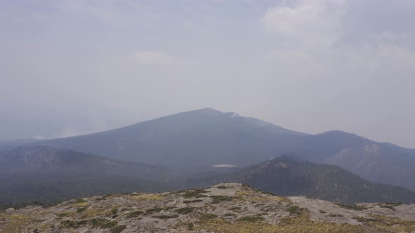 A closeup shot of Hispanic hikers sitting on top of the Tlaloc Mount on a gloomy day in Mexico fire