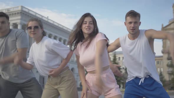 Middle Shot of Young Cheerful Friends Performing Modern Dance on City Square at Sunrise. Portrait of