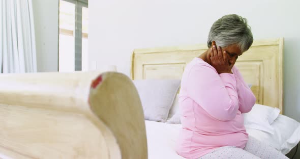 Tense senior woman sitting on bed in bedroom 4k