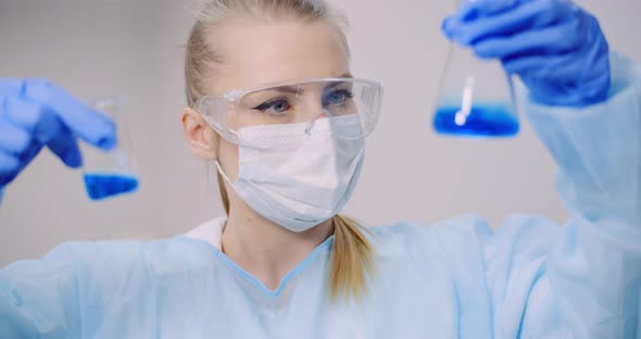 Female Scientist Holding Tubes and Flask with Liquid in Hands