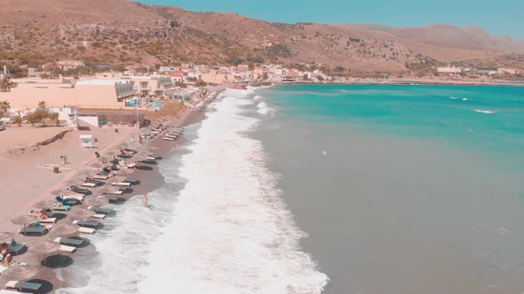 Drone flying close to shore with sunbeds.