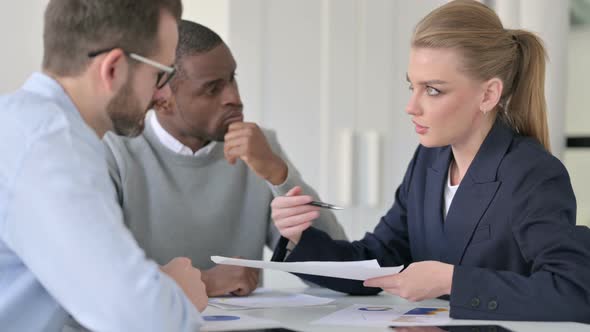 Businesswoman Explaining Documents to Male Colleagues