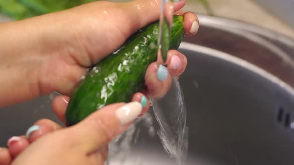 Closeup of a Woman Washing Fresh Cucumbers in the Kitchen Sink