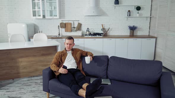 Young man sitting on sofa, using mobile phone