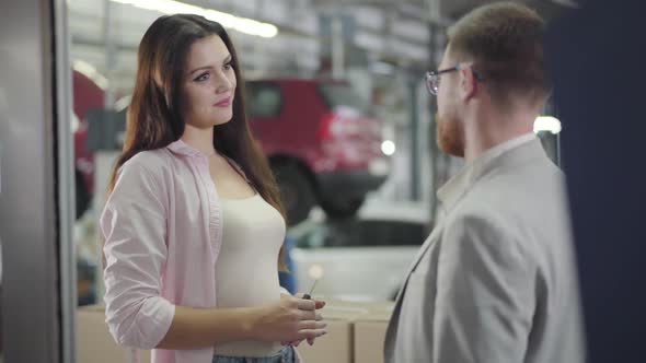 Portrait of Attractive Caucasian Female Car Dealer Giving Keys To the Buyer