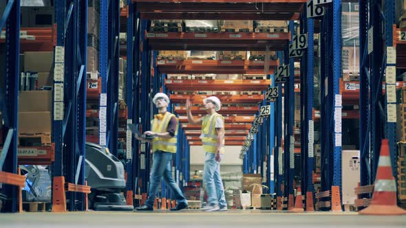 Workers and a Cyborg with a Cleaner Are Crossing the Warehouse