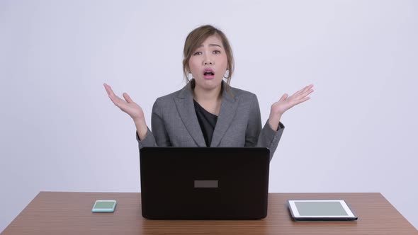 Young Confused Asian Businesswoman Shrugging Shoulders at Work