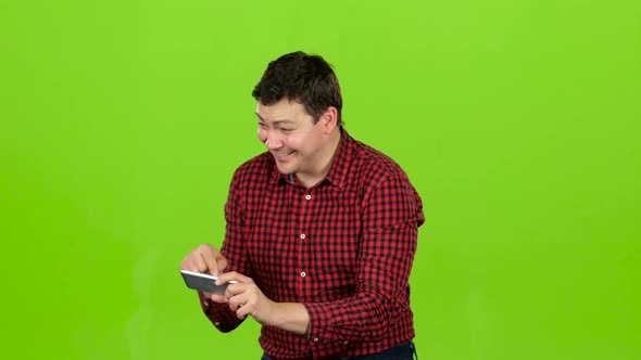 Man Takes Pictures on the Phone, He Is Happy and Cheerful. Green Screen