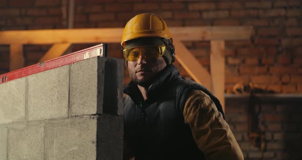 Male Builder Behind Brick Wall with Level