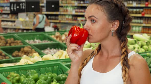 Beautiful Young Woman Smelling Paprika at the Supermarket