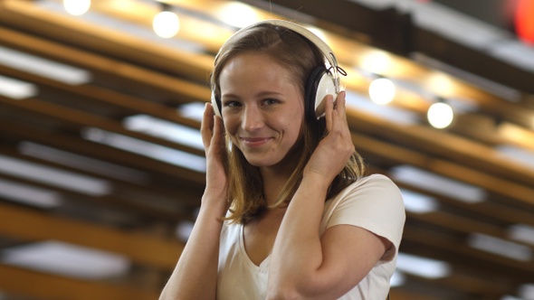 Nice young girl listening to music in headphones smiling