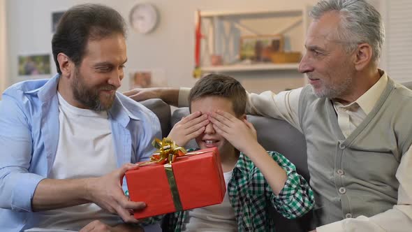 Boy Sitting With Eyes Closed, Father and Grandpa Giving Birthday Gift, Surprise